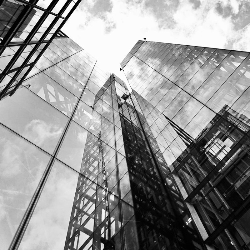 Organisation und Struktur -quadrat- Ansicht eines Hochhauses von unten, in der Glasfassade spiegeln sich Wolken